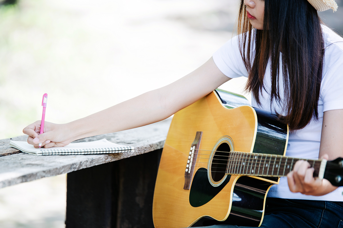 Portrait of beautiful girl playing the guitar with writing at n